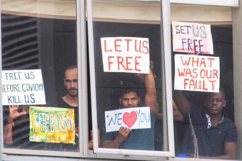 migrants holding signs at hotel window panama