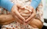 family caregiver holding elderly hand hospital