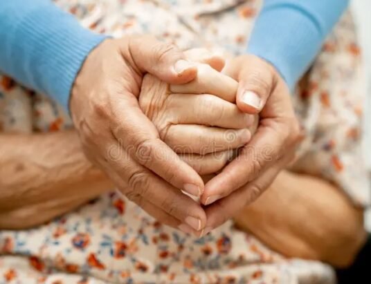 family caregiver holding elderly hand hospital