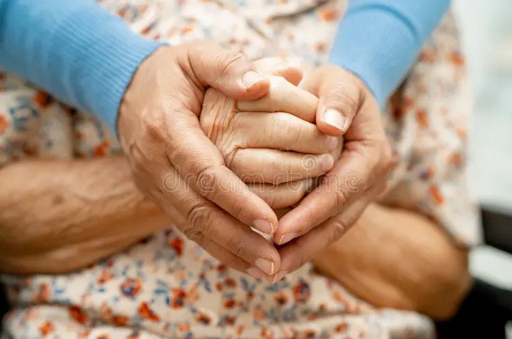 family caregiver holding elderly hand hospital