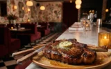 Luella Buckhead steakhouse dining room with oxblood velvet banquettes and steak.
